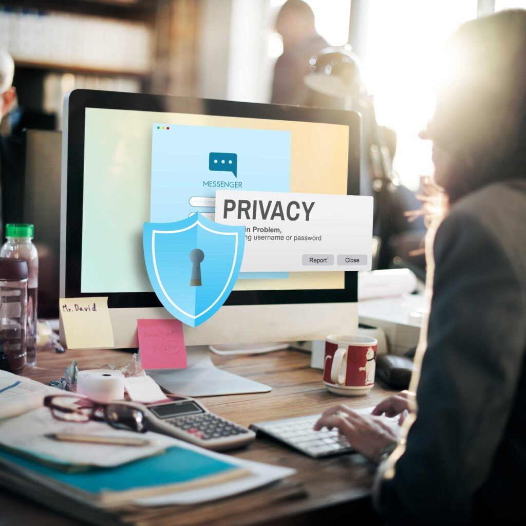 Office worker using a desktop computer with a privacy warning and digital security shield overlay, emphasizing online data protection and login confidentialit